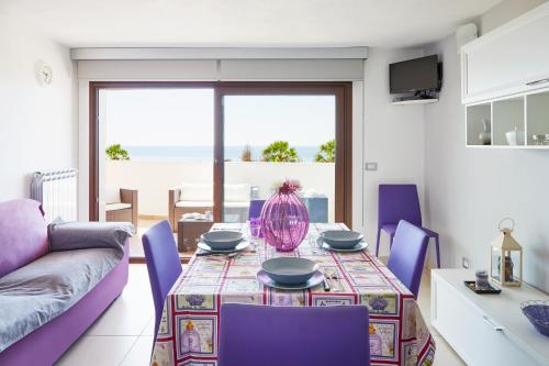 een woonkamer met een tafel en paarse stoelen bij Aura CaseSicule, only for Sea View Lovers, Modern Style Apartment in City Center, Wi-Fi in Pozzallo