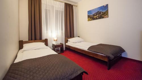 a hotel room with two beds and a red carpet at Hotel Graal Targowisko in Targowisko