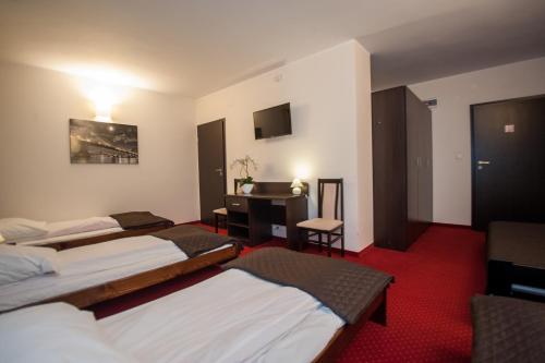 a hotel room with three beds and a desk at Hotel Graal Targowisko in Targowisko
