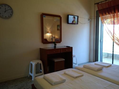 two beds in a room with a mirror and a vanity at Rooms To Let Giannis in Makrýgialos