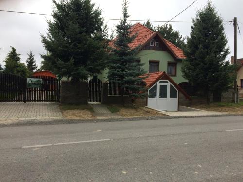 a house with a white door and a fence at Bakonyi Mamutfenyő Vendégház in Tés