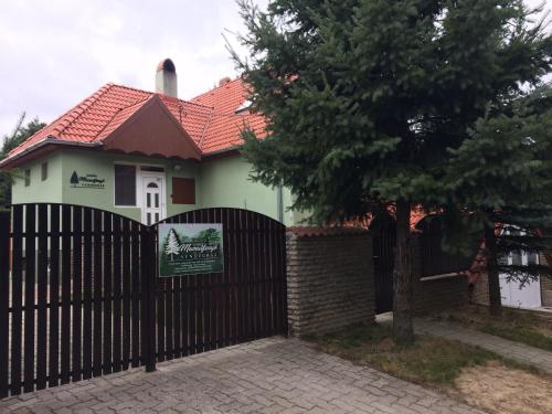 a house with a black fence and a tree at Bakonyi Mamutfenyő Vendégház in Tés