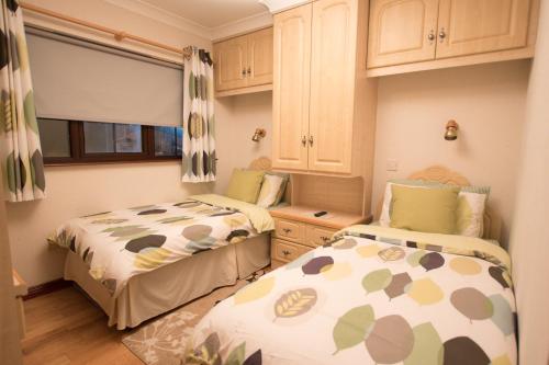 duas camas num pequeno quarto com armários em Rossgier Inn em Lifford