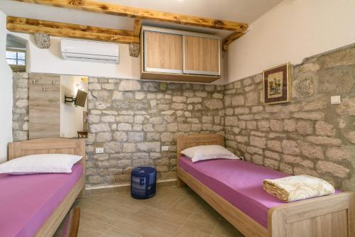 twee bedden in een kamer met een stenen muur bij Lorena in Trogir