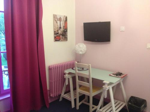 a room with a desk and a table and a tv at Hotel Couleurs Sud Centre-ville Gare Charleville-Mézières in Charleville-Mézières