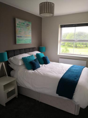 a bedroom with a bed with blue pillows and a window at James Cook's Retreat in Middlesbrough