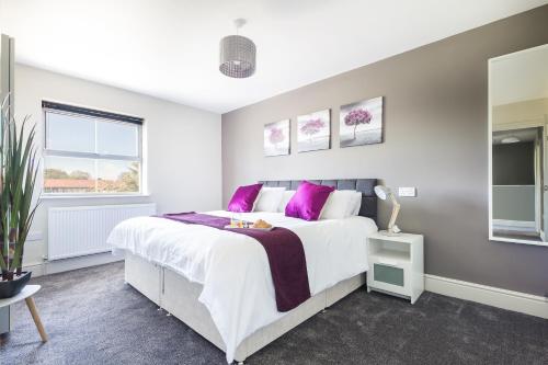 a bedroom with a large bed with purple pillows at James Cook's Retreat in Middlesbrough
