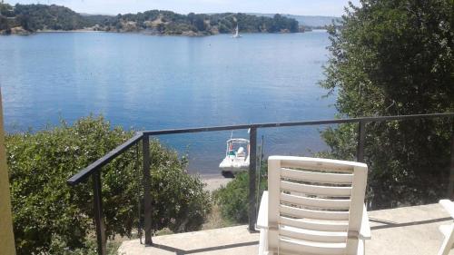 a white chair sitting on a balcony overlooking a body of water at Cabañas Bahia Radal in Villa Pehuenia