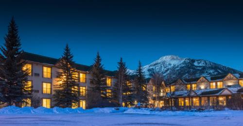 a hotel in the snow with a mountain in the background at Coast Canmore Hotel & Conference Centre in Canmore