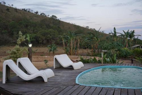 dos sillas blancas sentadas en una terraza junto a una piscina en Pousada Estância Macaúbas - en São Roque de Minas