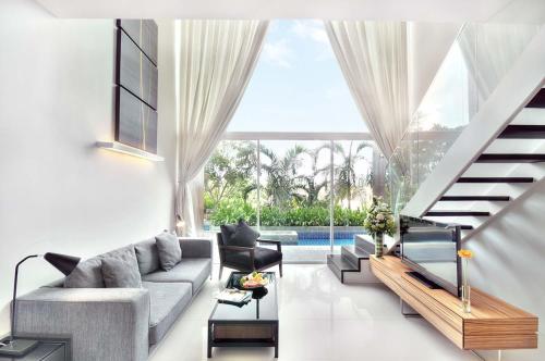 a living room with a couch and a staircase at Mida De Sea Hua Hin - SHA PLUS in Cha Am
