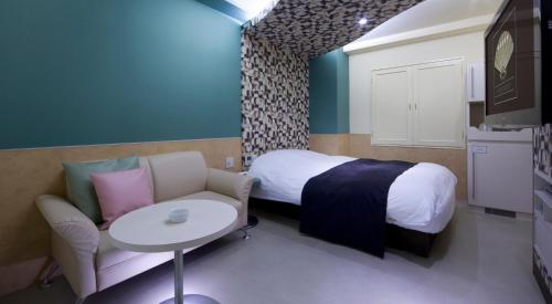 a bedroom with a bed and a table and a chair at Hotel Glow Yokkaichi (Adult Only) in Yokkaichi