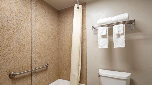 a bathroom with a toilet and a shower with towels at Best Western Center Inn in Virginia Beach