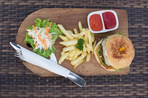 a wooden cutting board with a sandwich and french fries at Zia Hotel Kuta in Kuta
