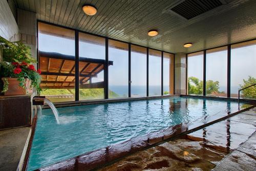 a large swimming pool in a building with windows at Atagawa Prince Hotel in Higashiizu