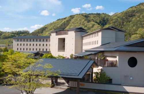a large white building with a mountain in the background at Iizaka Onsen Surikamitei Ohtori in Fukushima