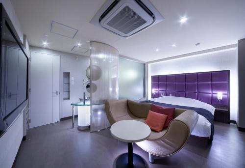 a bedroom with a bed and a couch and a table at Hotel Glow Yokkaichi (Adult Only) in Yokkaichi