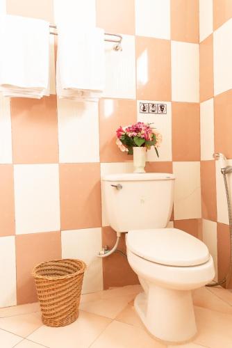 a bathroom with a toilet with a vase of flowers at PN Gold Resort in Bangsaen