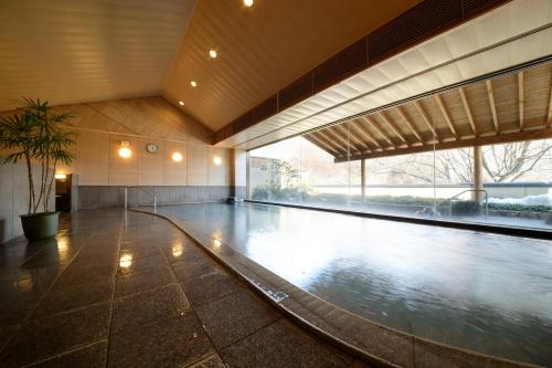a swimming pool in a building with a large window at Iizaka Onsen Surikamitei Ohtori in Fukushima