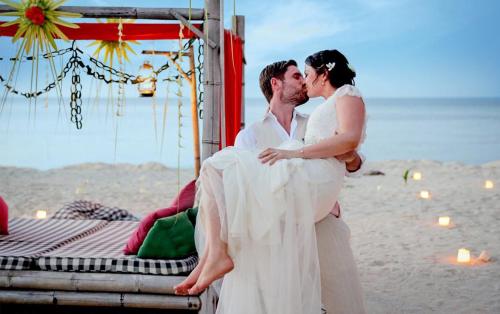 a bride and groom kissing on the beach at Hotel Tugu Lombok - CHSE Certified in Tanjung
