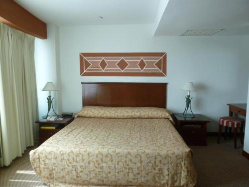 Schlafzimmer mit einem großen Bett mit einem Kopfteil aus Holz in der Unterkunft GOCOS Hotel in Klang