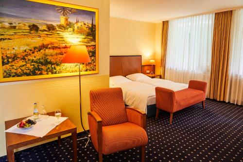 ピンネベルクにあるHotel Cap Polonioのベッド、テーブル、椅子が備わるホテルルームです。