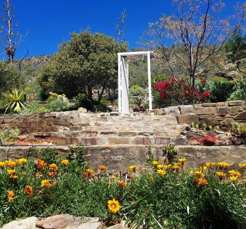 a garden with a white arch on a set of stairs with flowers at Montagu Little Sanctuary - Hot Spring Access at Special Rate in Montagu