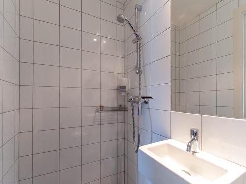 a white tiled bathroom with a sink and a shower at Fast Hotel Henningsvær in Henningsvær