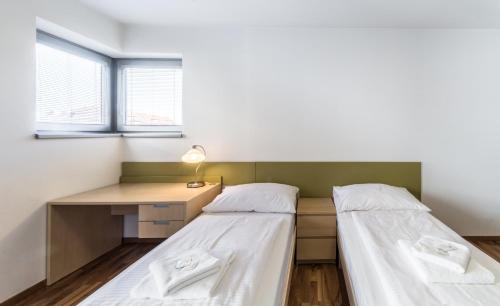 two beds in a room with a desk at Penzion Palouček in Prague