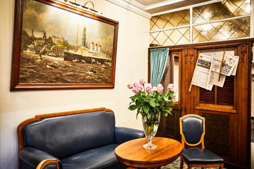 a waiting room with a couch and a table and a vase of flowers at Hotel Cap Polonio in Pinneberg
