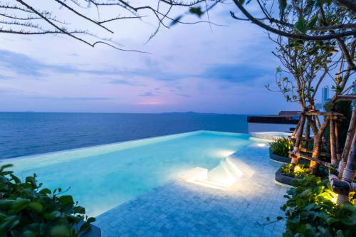 a swimming pool with the ocean in the background at U Jomtien Pattaya in Jomtien Beach