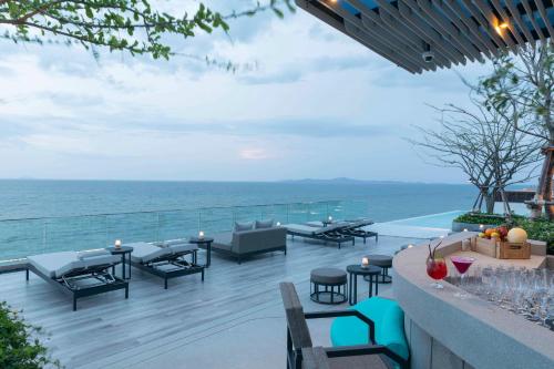 an outdoor patio with tables and chairs and the ocean at U Jomtien Pattaya in Jomtien Beach