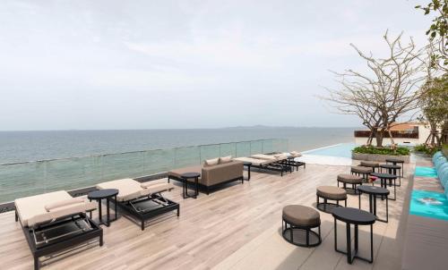 a patio with chairs and tables next to a swimming pool at U Jomtien Pattaya in Jomtien Beach