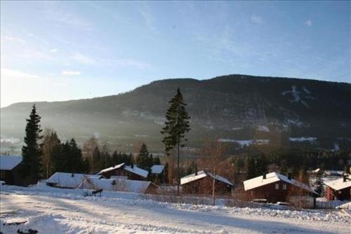uma aldeia coberta de neve com uma montanha ao fundo em Hafjell Grenda lejligheder em Hafjell