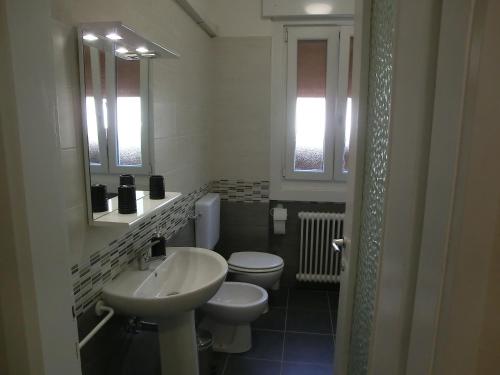 La salle de bains blanche est pourvue d'un lavabo et de toilettes. dans l'établissement Le Rose, à Trieste