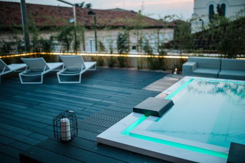 a swimming pool on a roof with chairs and a heater at JO Hotel in Marano Lagunare