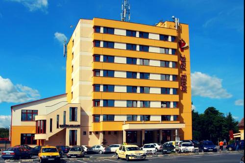 a yellow building with cars parked in a parking lot at Hotel Parc Sibiu in Sibiu