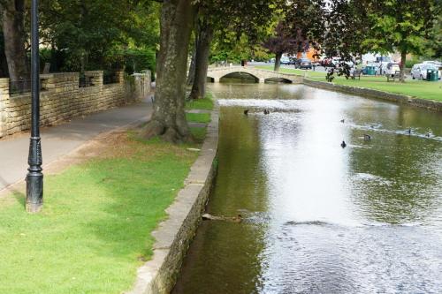 a body of water with ducks swimming in it at Chester House Hotel in Bourton on the Water