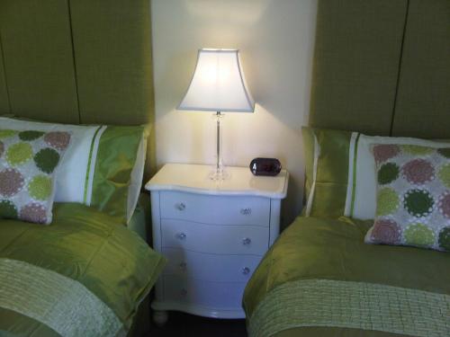 a bedroom with two beds and a lamp on a night stand at Plumpton House in Ashford
