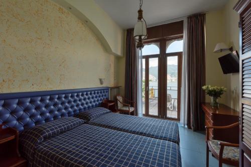 een slaapkamer met een blauw bed en een raam bij Hotel Malcesine in Malcesine