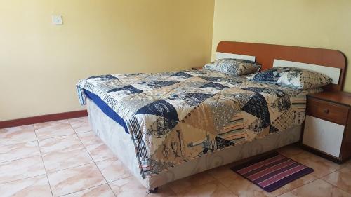 a bedroom with a bed with a quilt on it at Maoni Guest House in Blantyre