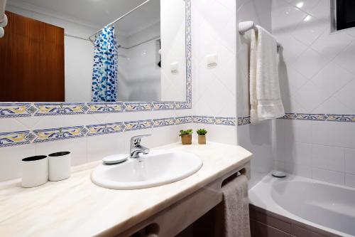 a bathroom with a sink and a mirror and a tub at LOTUS VILLA, Albufeira in Albufeira