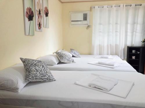 two beds in a bedroom with white sheets and pillows at RQS Hostel in Tacloban