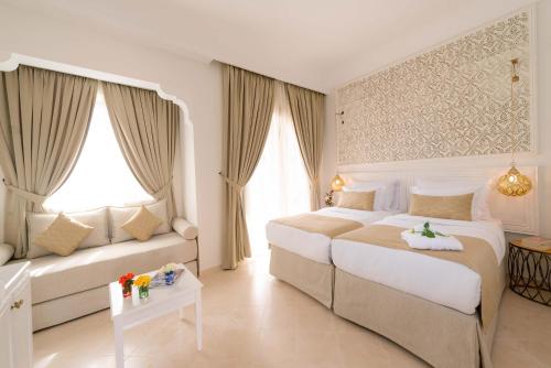 a hotel room with two beds and a couch at Marrakech Ryads Parc All inclusive in Marrakech