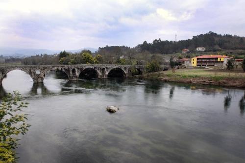 a bridge over a river with a rock in the water at Casa da Ponte do Porto in Amares