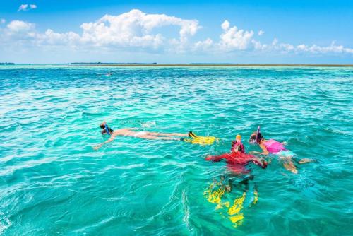 three people swimming in the water in the ocean at Villa Lala in Kiwengwa