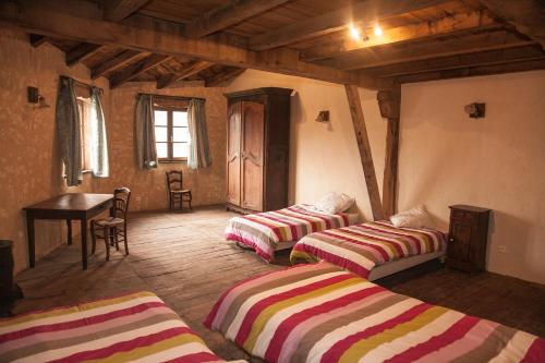 a room with two beds and a table and a desk at La ferme des Cévennes in Florac Trois Riviere