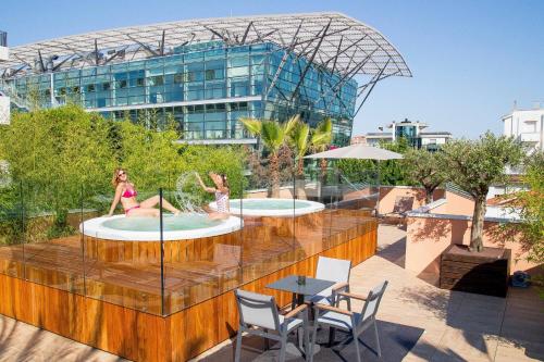 duas raparigas a brincar em duas piscinas no telhado de um edifício em Metropol Ceccarini Suite - Luxury apartments em Riccione