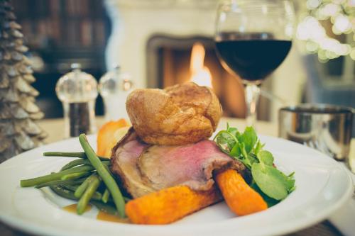 a plate of meat and vegetables with a glass of wine at George Hotel, BW Signature Collection in Norwich