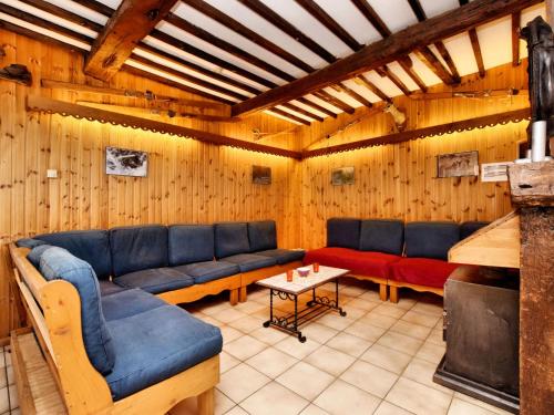 Villers-Sainte-GertrudeにあるVibrant Holiday Home in Durbuy with Gardenの木製の壁のリビングルーム(青いソファ、テーブル付)